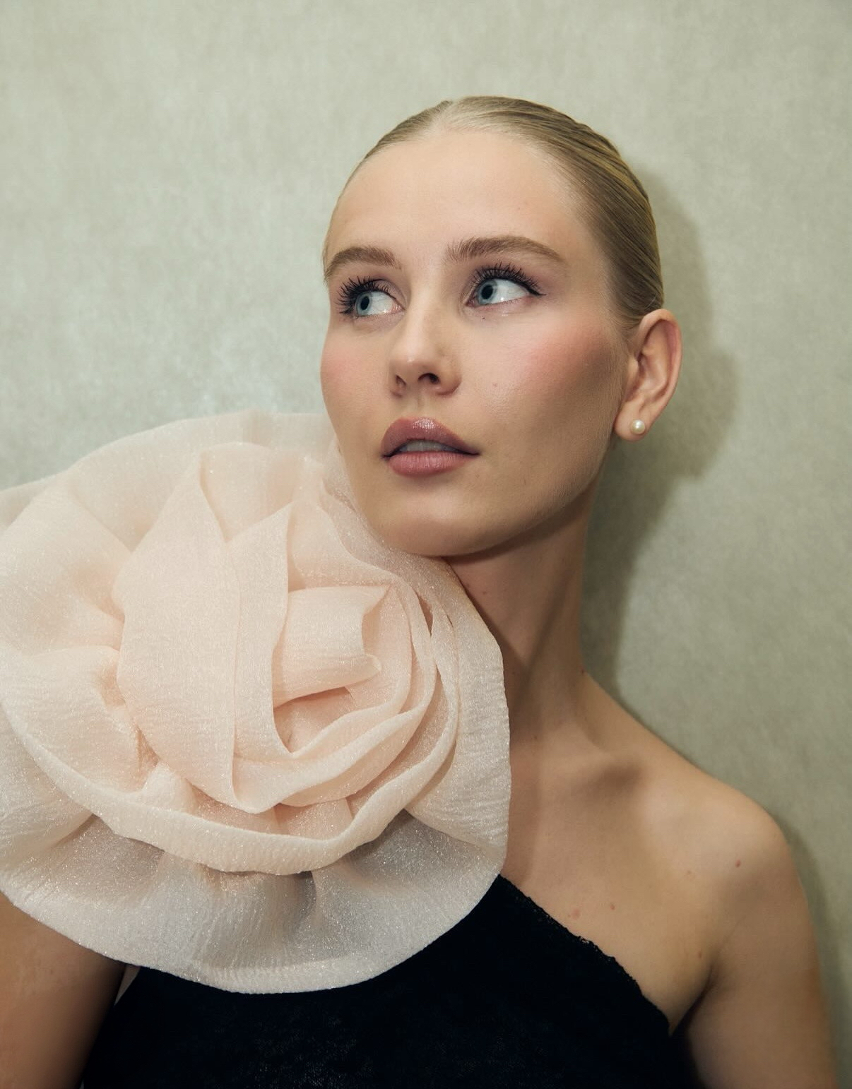 Pearl earrings styled with a black dress and sculptural flower